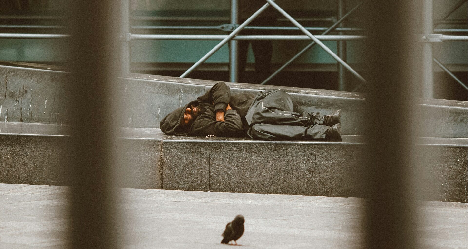 a homeless man lying down sleeping rough on the street