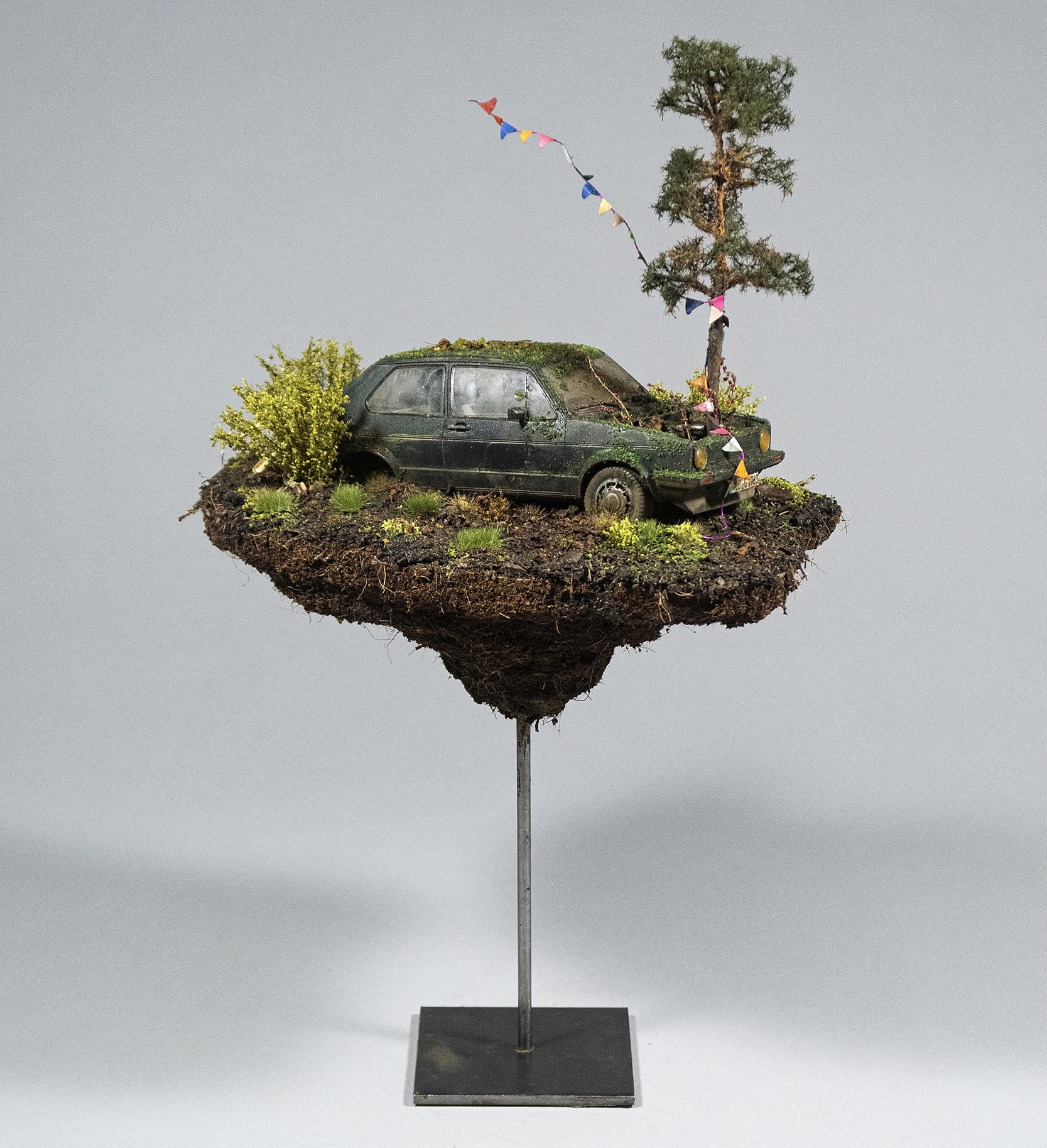 a hand-sculpted miniature by Simon Laveuve of an abandoned car with a tree growing out of the hood