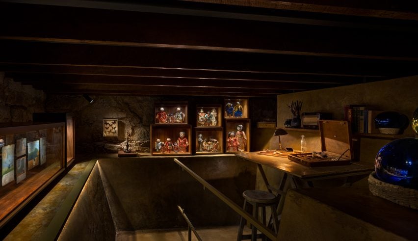 A dark room with a doll collection and a desk with paints on display