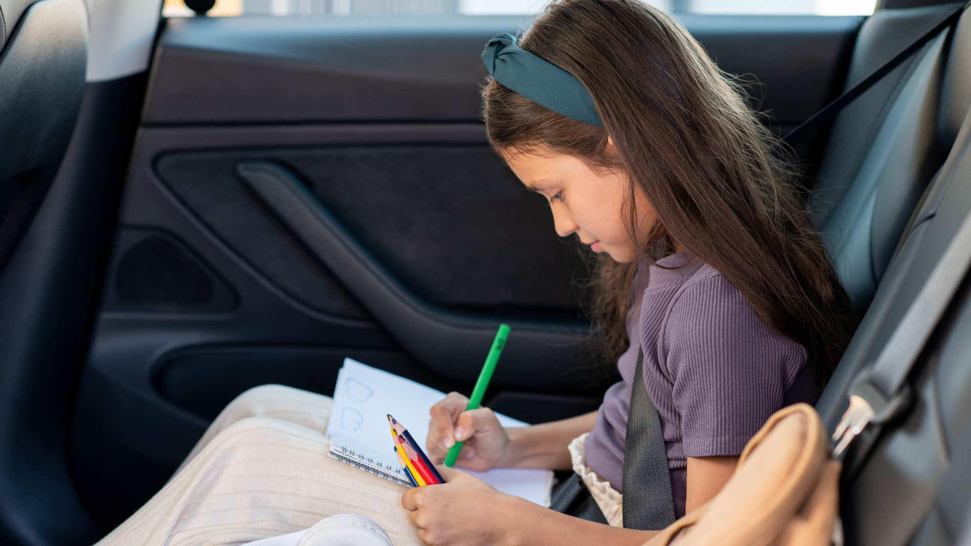 young kid coloring in car backseat