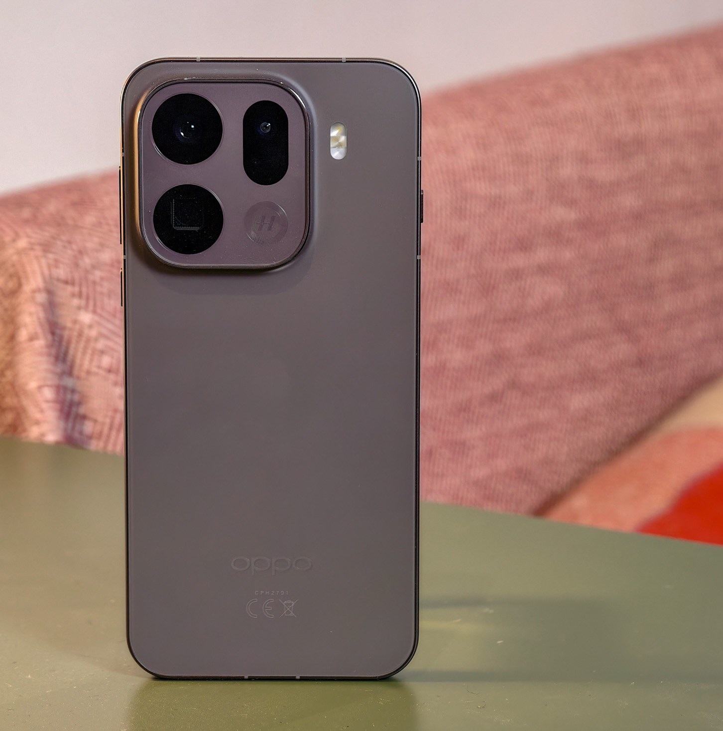 Oppo Find X9 Pro resting on a green table in front of a sofa