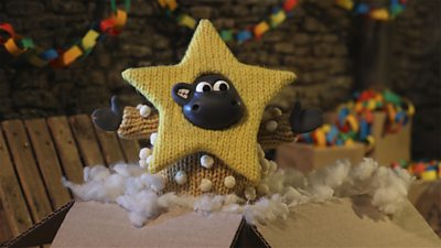 A little claymation sheep smiles as his head emerges from a knitted yellow star