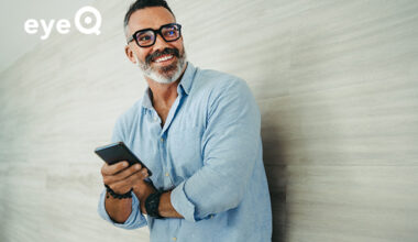 eyeQ a man holding his smartphone and smiling