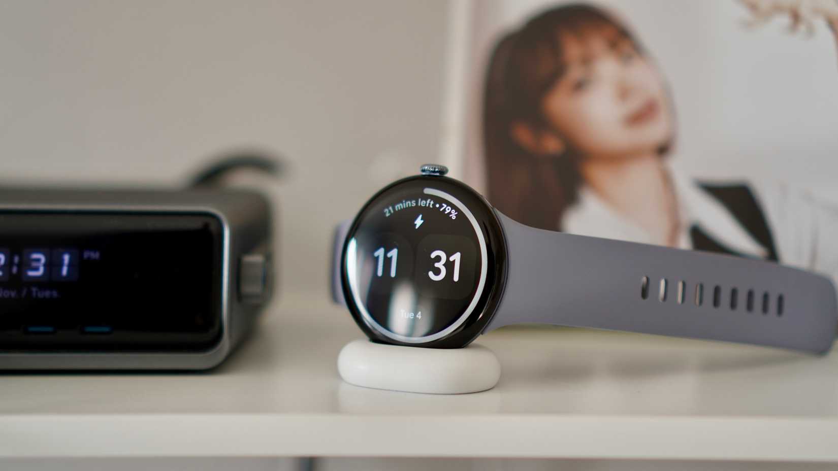 A Google Pixel Watch 4 sitting on a charger and showing the time and minutes left to full charge