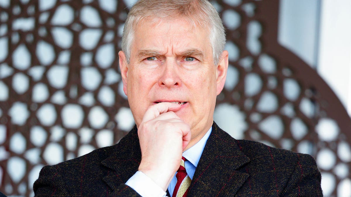 A close-up of Prince Andrew looking pensive with his finger to his mouth.