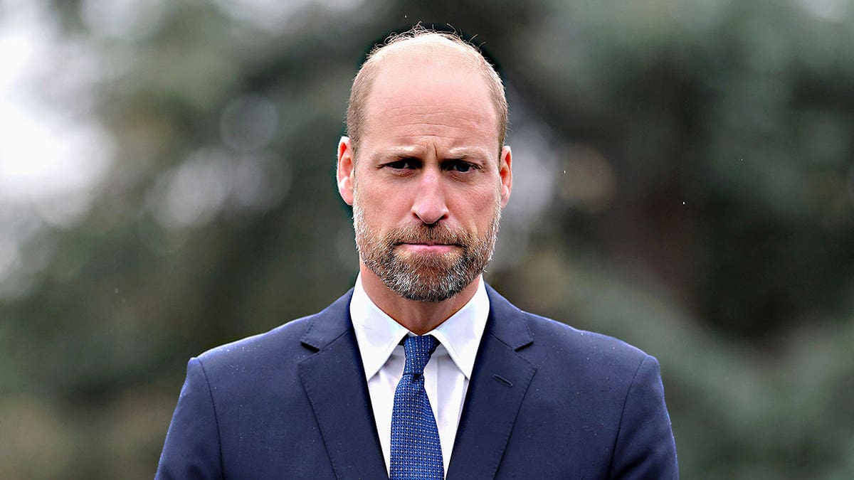 A close-up of Prince William in a dark blue suit looking pensive while completing a royal engagement.