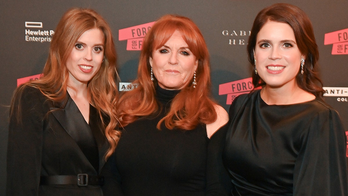 Sarah Ferguson wearing black as she stands with her daughters on the red carpet wearing matching attire.