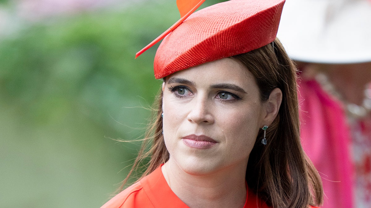 A close-up of Princess Eugenie wearing a coral dress and a matching hat.
