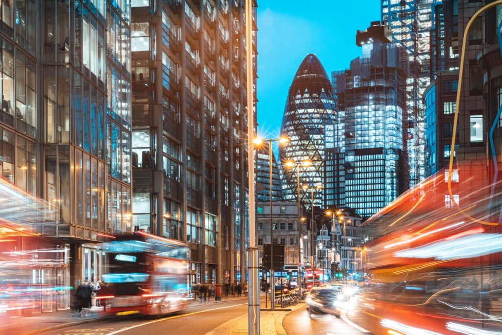 a busy london road at night, with blurry buses and cars