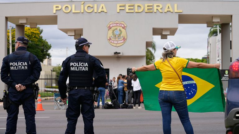 A supporter of Bolsonaro holds a Brazilian flag outside the federal police headquarters in Brasilia. Pic: AP