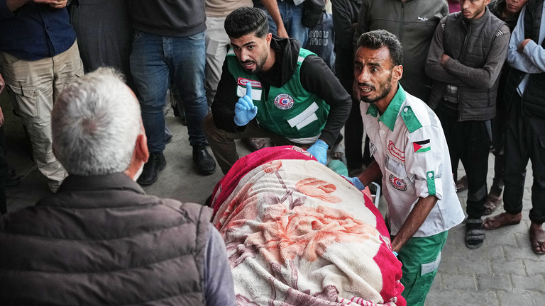 Medics carry the body of a person killed in Israeli airstrikes in  Deir al Balah. Pic: AP