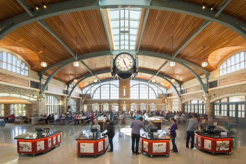 Spacious dining hall with arched ceiling, large clock, and groups of people.