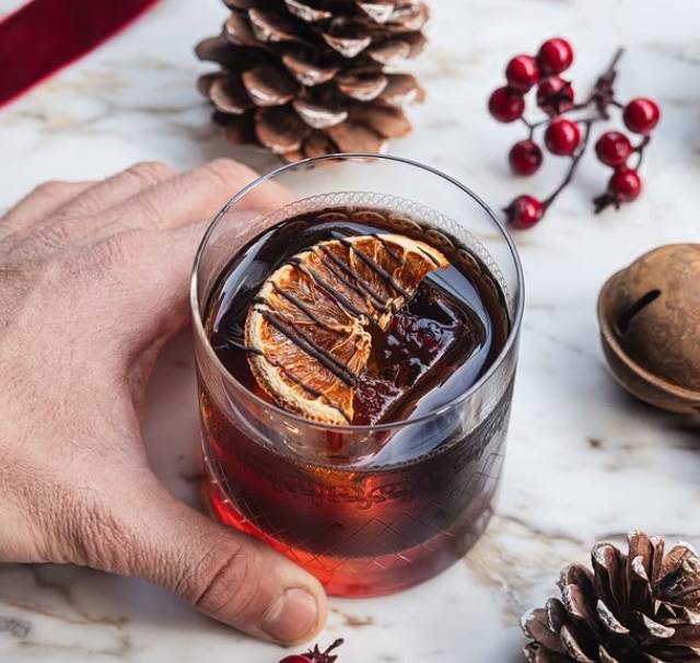 story cellar festive cocktail with orange and surrounded by pinecones and berries