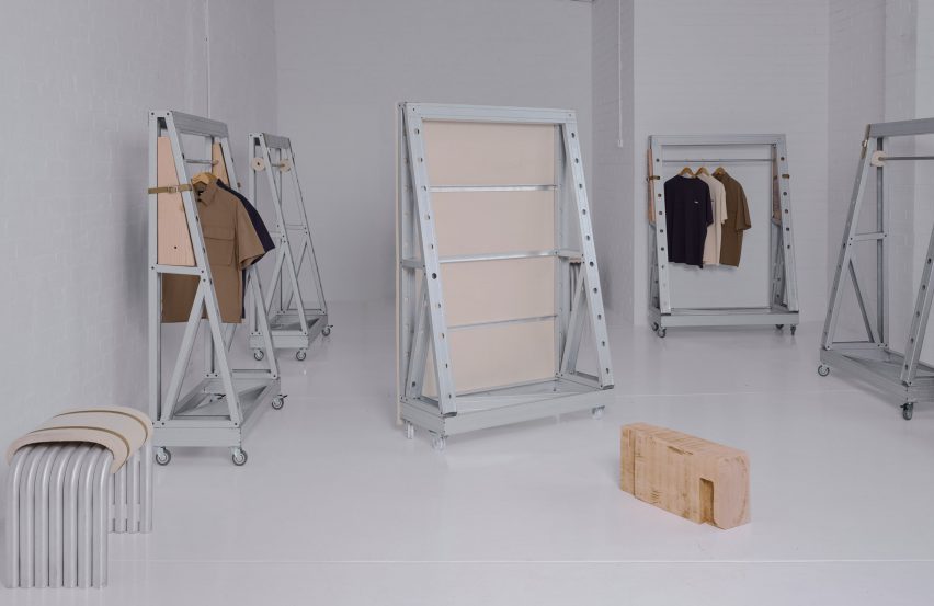 Minimalist industrial furniture installation featuring steel and wood modular frames on caster wheels in a white gallery space.