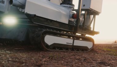 An autonomous, tracked robot sits on a dirt patch.
