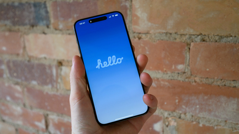 A hand holding an iPhone showing hello on screen.