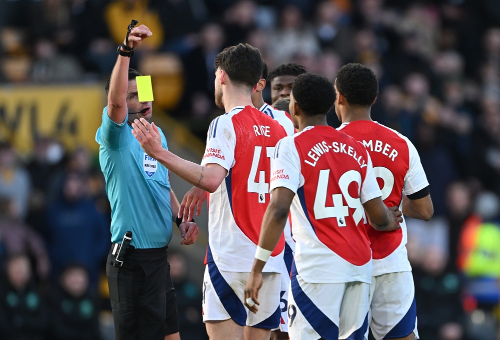 WOLVERHAMPTON, ENGLAND: Referee Michael Oliver drops a yellow card before showing Myles Lewis-Skelly of Arsenal a red card after he fouled Matt Doh...