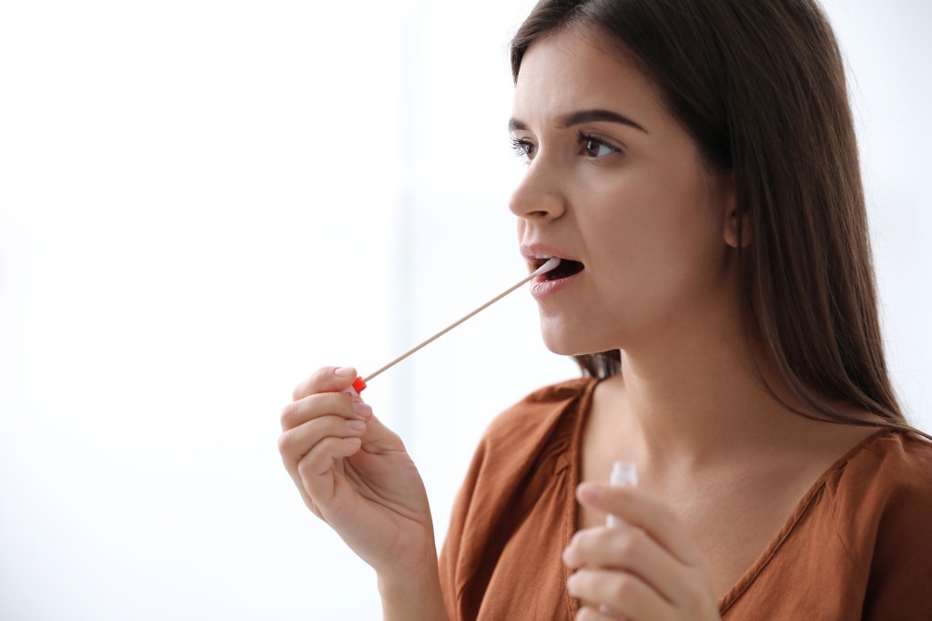 A woman collects a DNA sample with an oral swab.