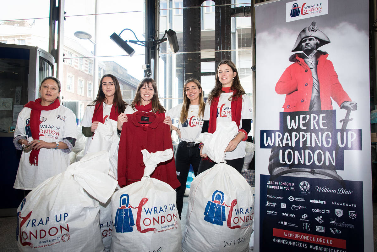 volunteers standing at a drop off point with big bags full of winter coats