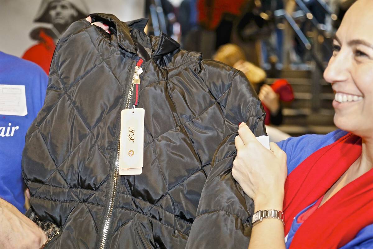 a volunteer holding up a donated coat