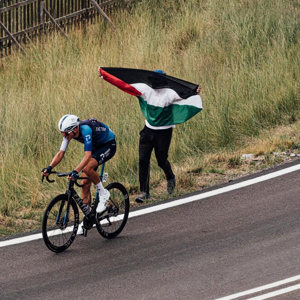Israel-Premier Tech’s Marco Frigo rides past spectator with Palestine flag, stage 7, 2025 Vuelta (cropped)