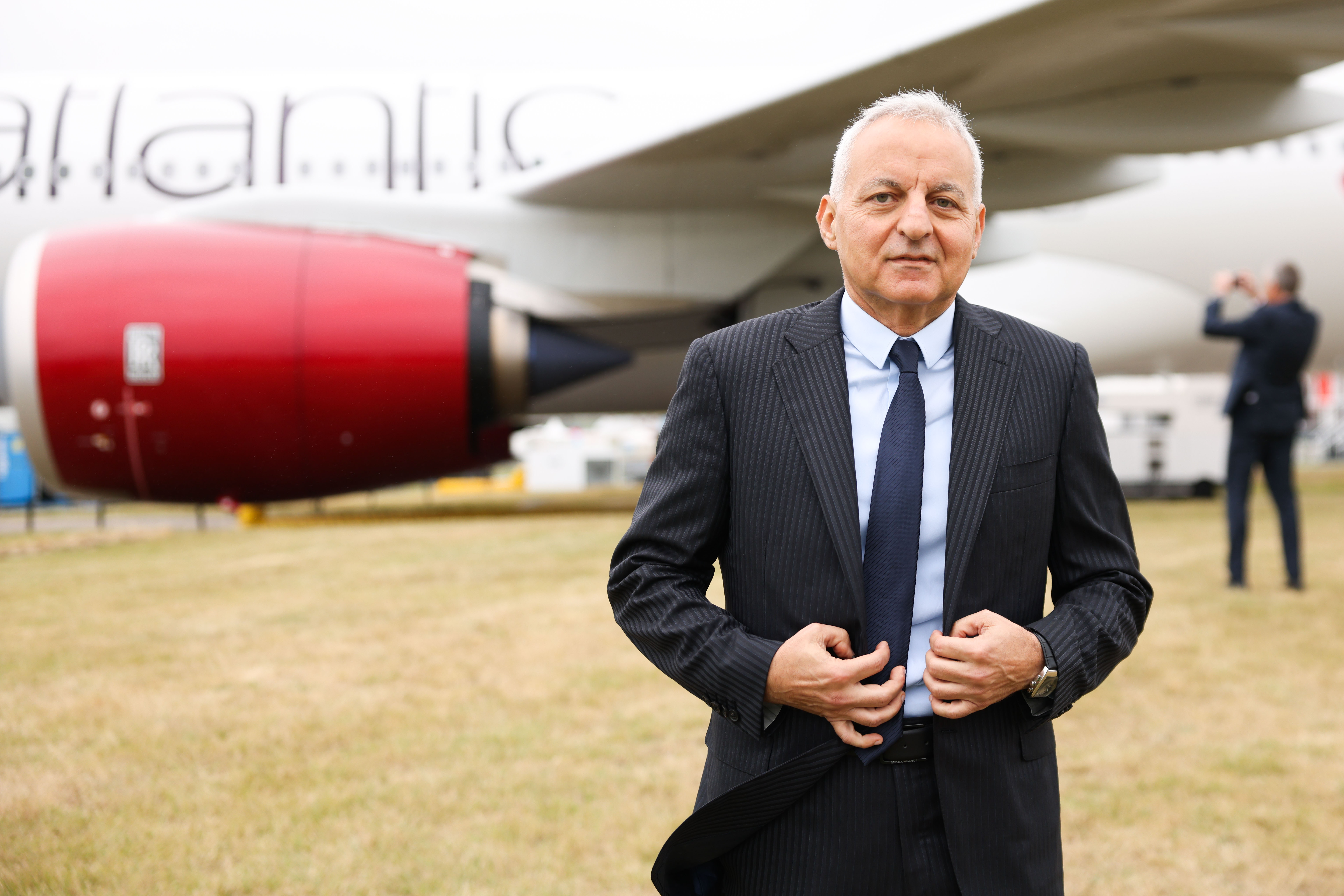 Tufan Erginbilgic, CEO of Rolls-Royce Holdings Plc, standing in front of a red jet engine at the Farnborough International Airshow.