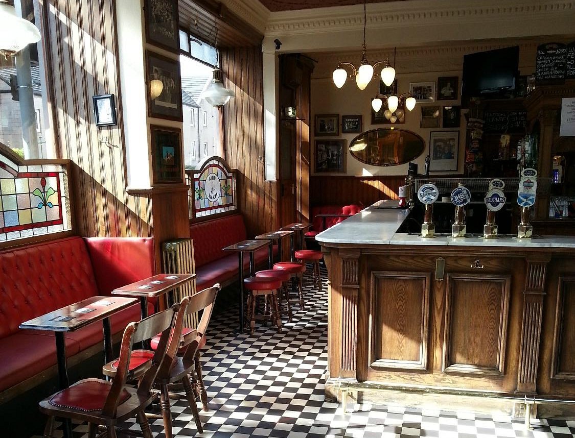 Interior of the Diggers - Athletic Arms pub with red booths and a bar.