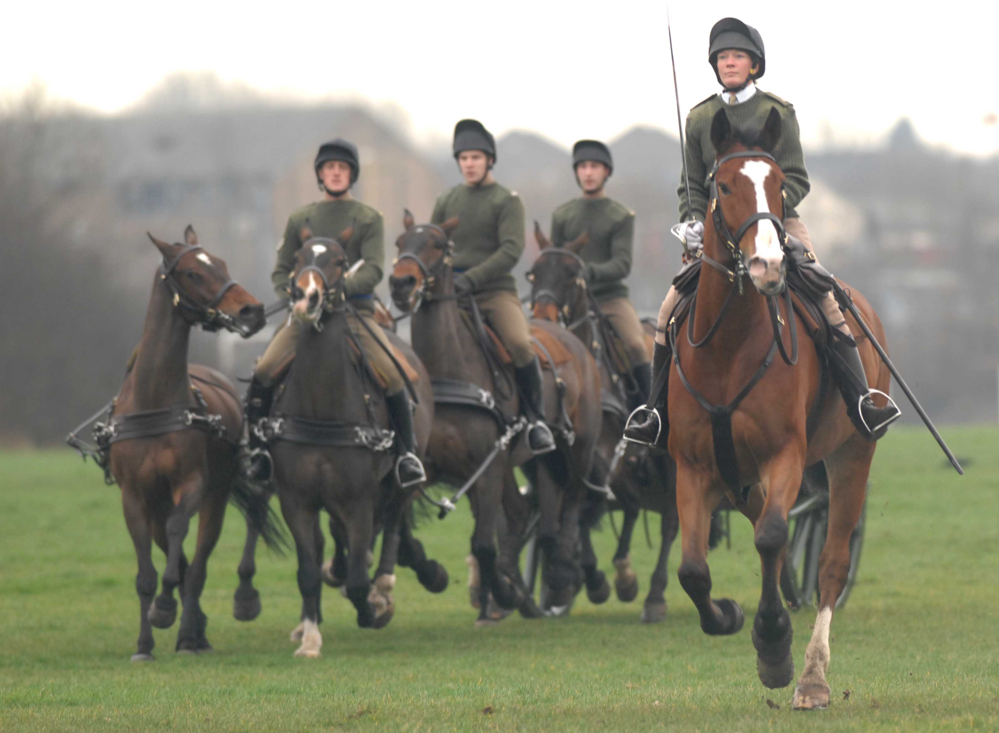Major Erica Bridge, the first female commander of the King's Troop, Royal Horse Artillery, on horseback with a sword leading other horses and riders.