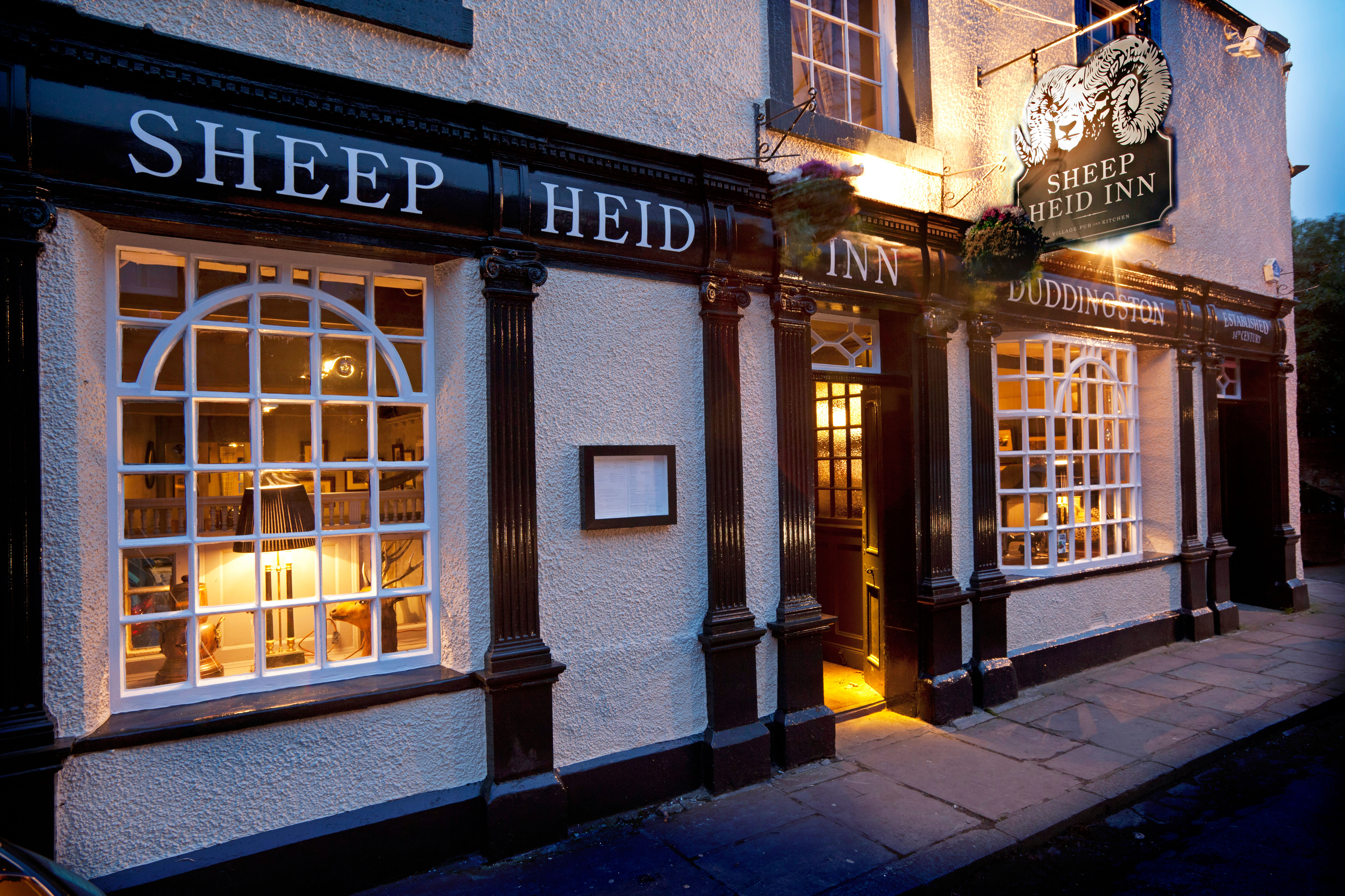 The Sheep Heid Inn in Duddingston Village, Edinburgh, with warm lights visible through its windows.