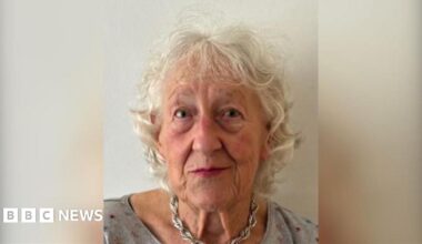 A police car stationed outside a semi-detached 1930s-style house on Kingsbury Avenue. There is police tape across the drive and a blue car parked on it.