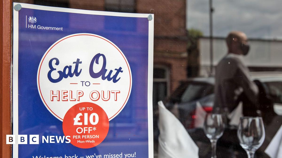An Eat Out to Help Out poster in a window with two wine glasses and a blurred reflection of a customer