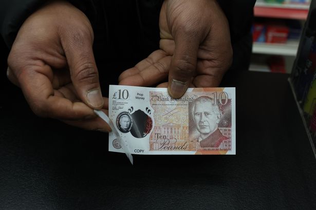 Rajee Gamage, 45, owner of PXK Booze, holds a fake £10 note used on County Road, Liverpool.