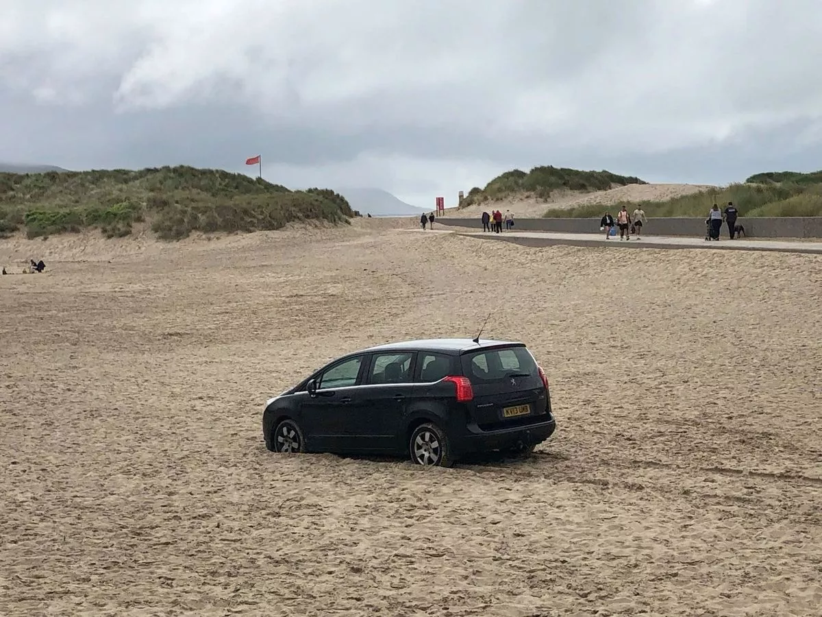 A Peugeot hatchback became stranded on Barmouth’s harbour beach within sight of 'Dum Dum', the resort’s carved wooden figure