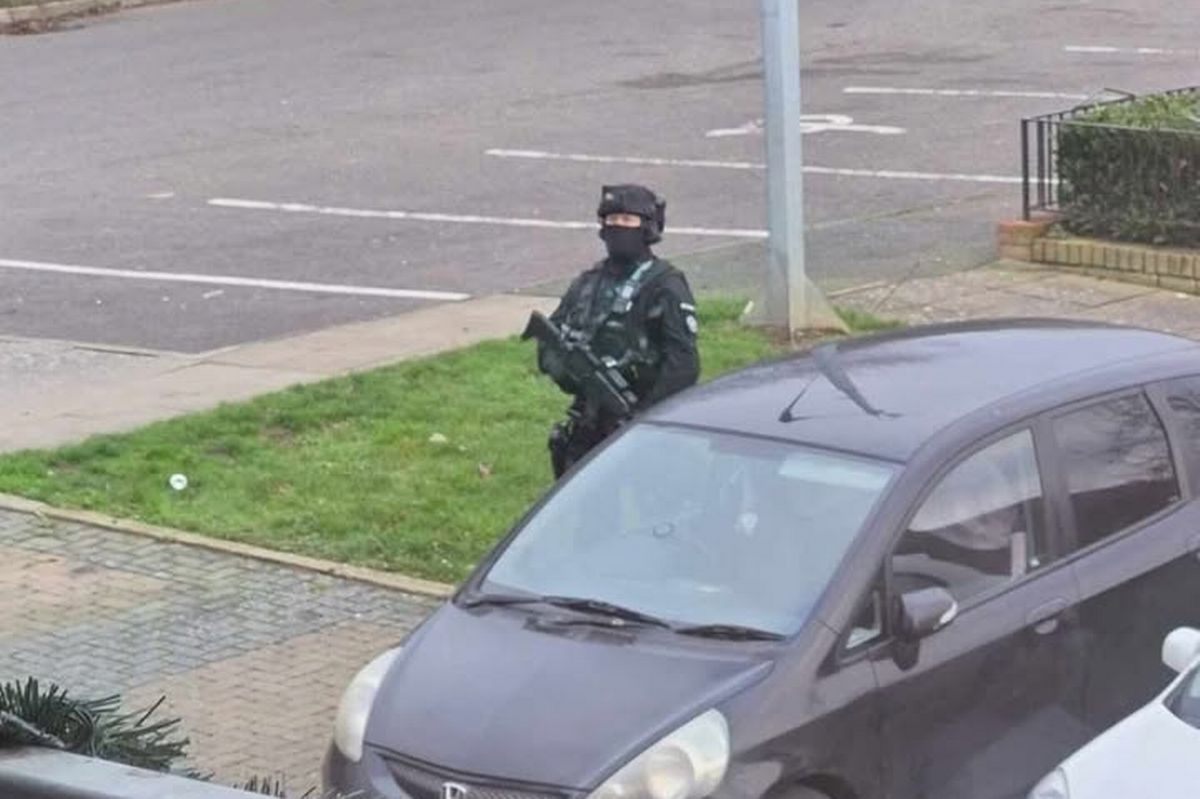 Armed officer standing outside of a block of flats. 