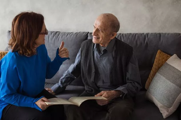 Happy female volunteer reading to an elderly man at nursing home