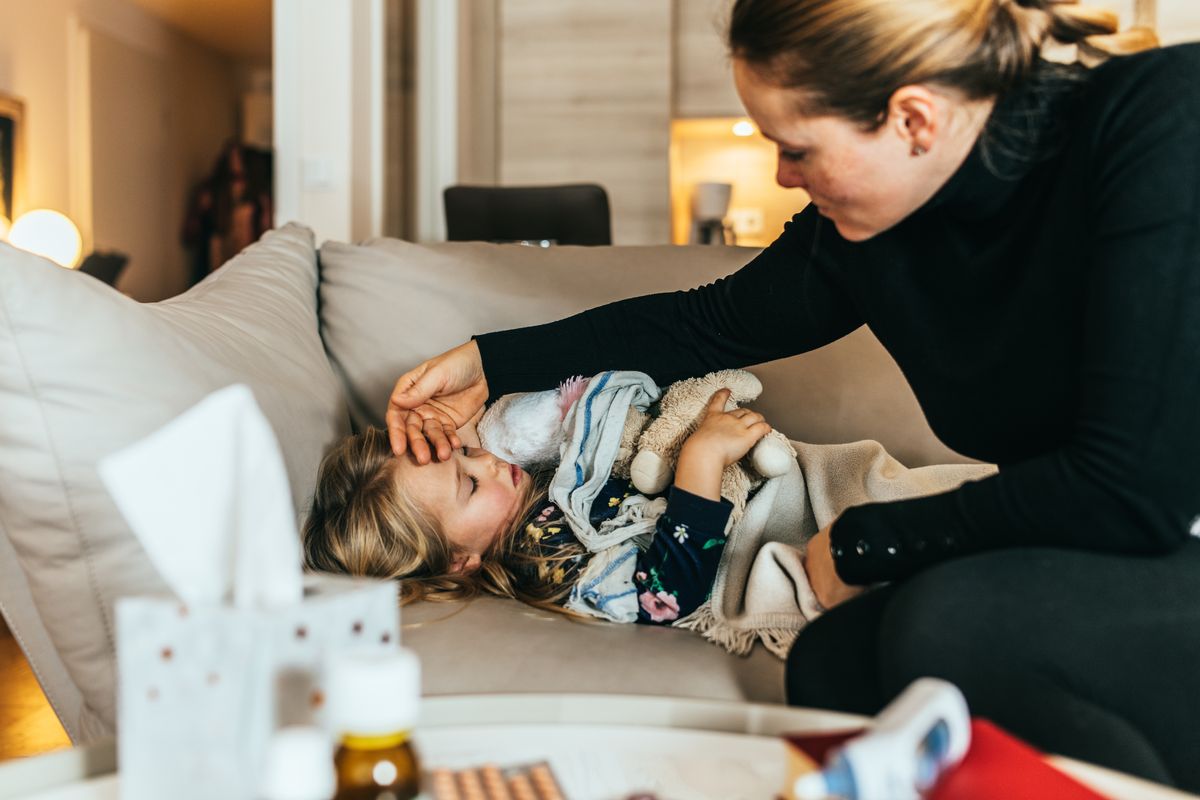 Woman using her hand to check temperature of her child.