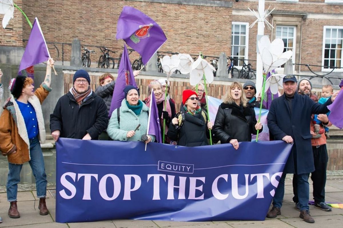 Protesters with flags and banners outside large curved civic building