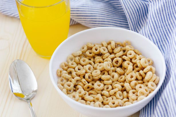 Hoop-style breakfast cereal on a table with a glass of orange juice next to it