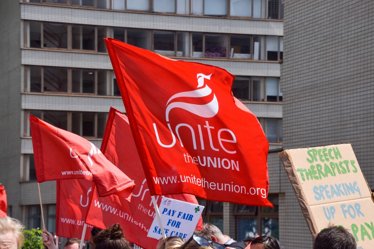 Unite union members hold union flags at the picket line