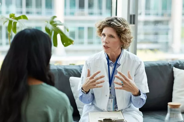 Healthcare expert guiding patient while sitting on sofa in hospital lobby