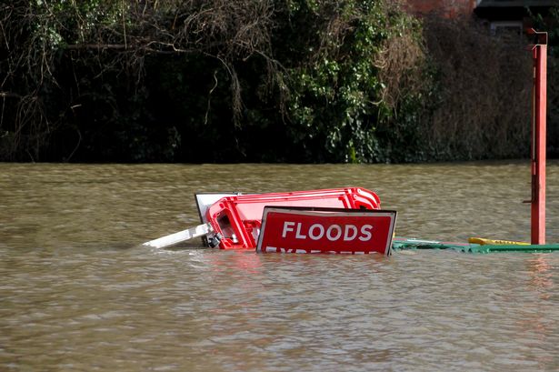 Floods flowing over a sign warning of floods