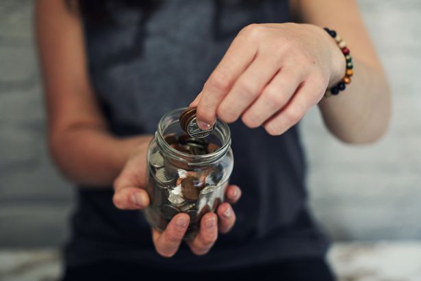 Young woman putting money into a jar