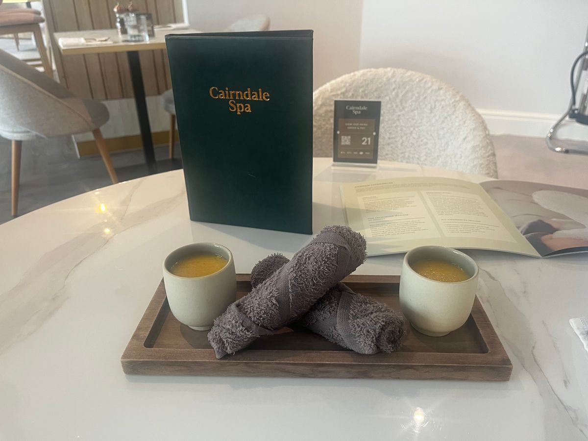 Small cups of smoothies beside two hot towels on a table