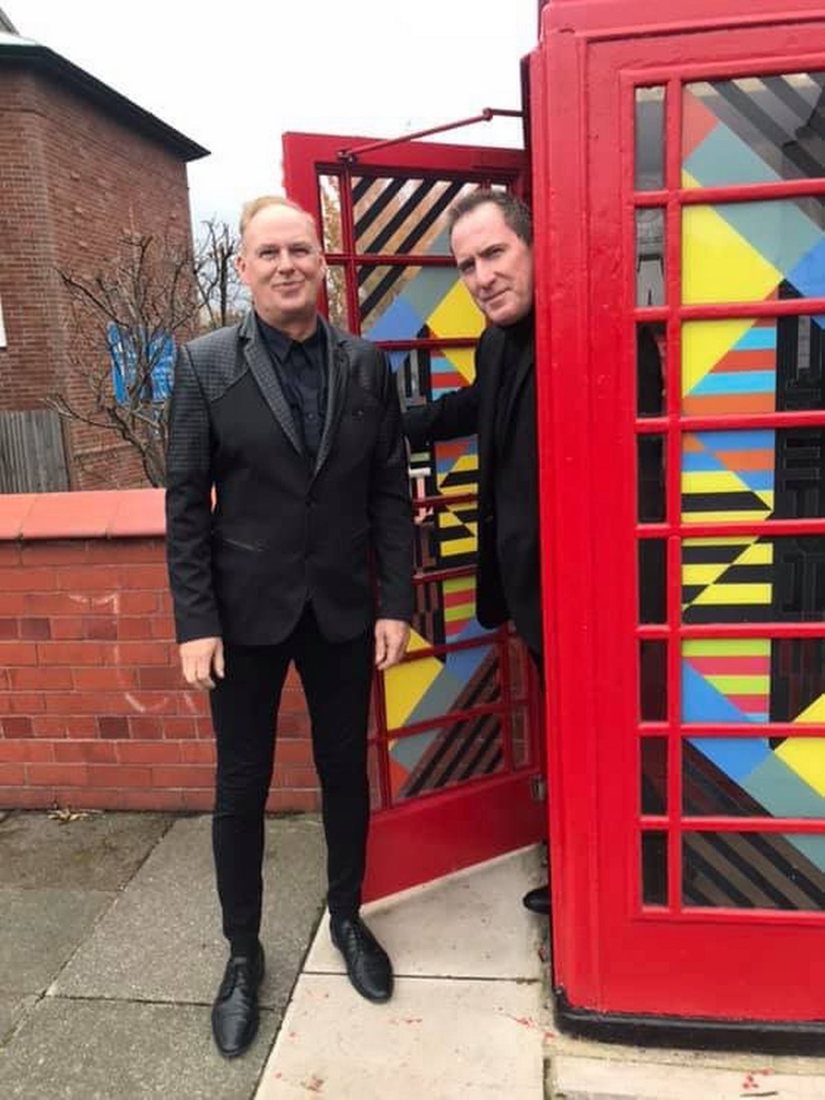 OMD founding members Paul Humphreys (left) and Andy McCluskey inside the red phone box monument to the band on Greenwood Road in Wirral.