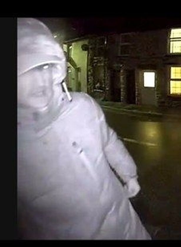 A man with his hood up outside a home