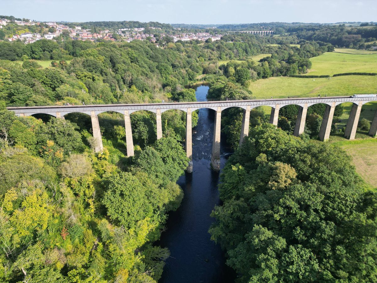 Pontcysyllte Aqueduct, built by Thomas Telford, and a World Heritage Site, reflecting in the River Dee, with incidental people walking across, near Llangollen, County Borough of Wrexham, Wales, UK