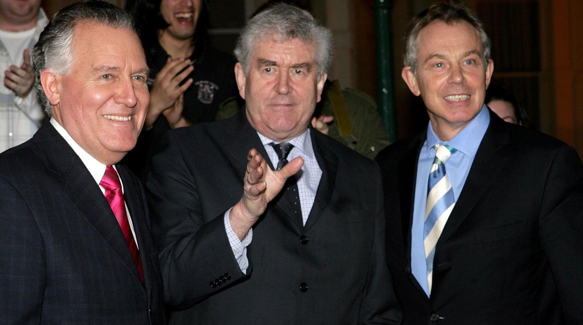 Three men in suits smiling at a camera