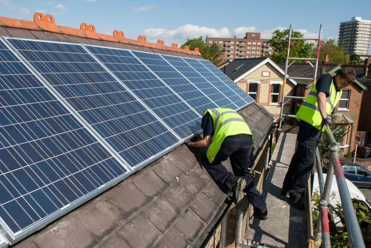 Contractors in high vis installing solar panels on rooftop in Hackney