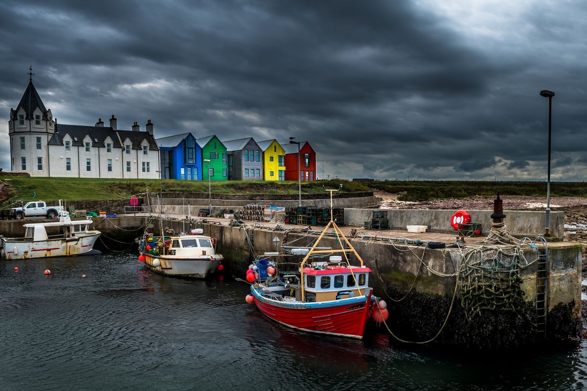 Scenic Harbor With Fishing Boats And Colorful Apartment Houses At John o'Groats In Scotland