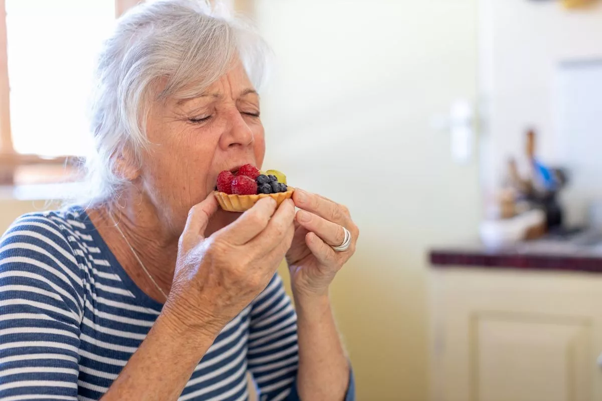 Senior woman enjoying eating a fruit tart